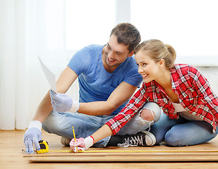 Image showing smiling couple measuring wood flooring