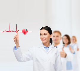 Image showing smiling female doctor pointing to cardiogram