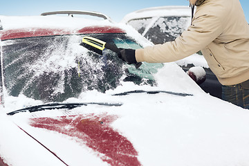 Image showing man cleaning snow from car windshield with brush