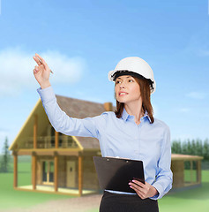 Image showing smiling businesswoman in helmet with clipboard