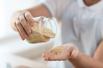 Image showing close up of male emptying jar with quinoa