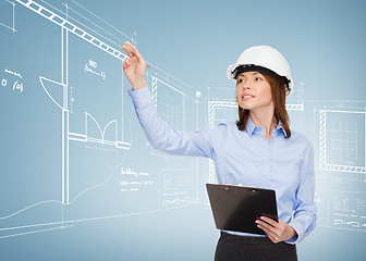 Image showing smiling businesswoman in helmet with clipboard