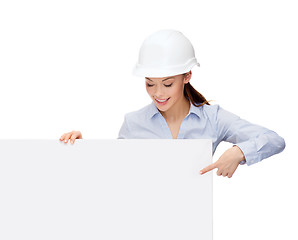 Image showing businesswoman in helmet pointing finger to board