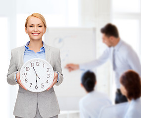 Image showing smiling businesswoman with wall clock