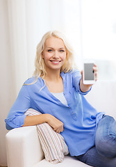 Image showing smiling woman with blank smartphone screen at home