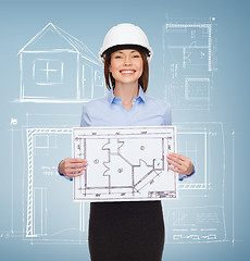 Image showing smiling businesswoman in helmet showing blueprint