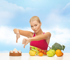 Image showing woman with fruits showing thumbs down to cake