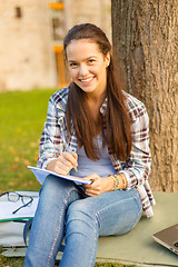 Image showing smiling teenager writing in notebook