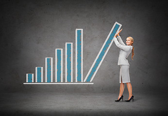 Image showing young smiling businesswoman pushing up chart bar