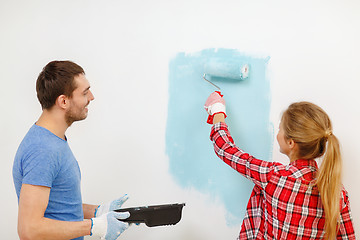 Image showing smiling couple painting wall at home