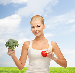 Image showing smiling woman holding heart symbol and broccoli