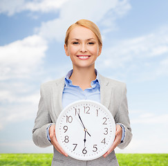 Image showing smiling businesswoman with wall clock