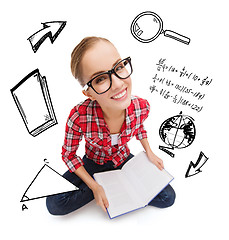 Image showing smiling teenage girl in eyeglasses reading book