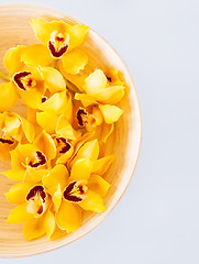 Image showing closeup of wooden bowl with orchid flowers