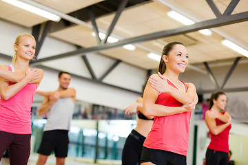 Image showing group of smiling people stretching in the gym