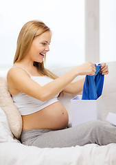 Image showing smiling pregnant woman opening gift box