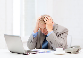 Image showing upset older businessman with laptop and telephone