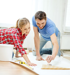 Image showing smiling couple smearing wallpaper with glue