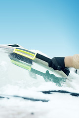 Image showing man cleaning snow from car windshield with brush