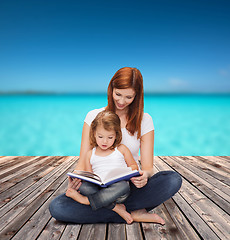 Image showing happy mother with adorable little girl and book