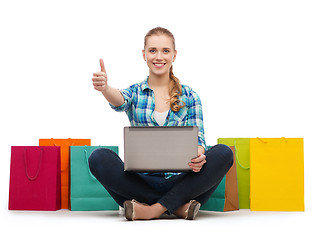 Image showing smiling girl with laptop comuter and shopping bags