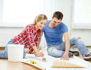Image showing smiling couple smearing wallpaper with glue