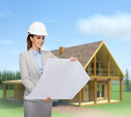 Image showing smiling architect in white helmet with blueprints