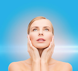 Image showing beautiful woman touching her face and looking up