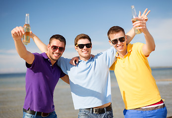 Image showing male friends on the beach with bottles of drink