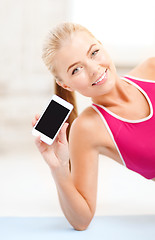 Image showing smiling woman lying on the floor with smartphone