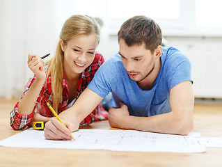 Image showing smiling couple looking at blueprint at home