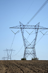 Image showing Electricity pylons in ploughed land