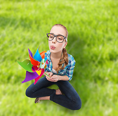 Image showing woman in eyeglasses sitting on floor with windmill