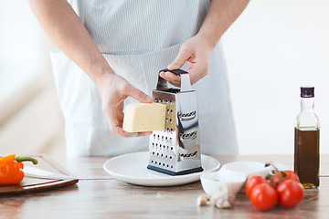 Image showing close up of male hands grating cheese