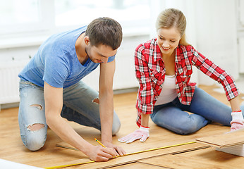 Image showing smiling couple measuring wood flooring