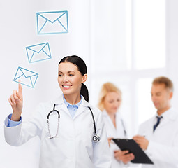 Image showing smiling female doctor pointing to envelope