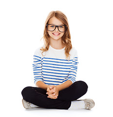 Image showing smiling girl in eyeglasses sitting on floor