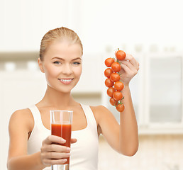 Image showing smiling woman holding glass of juice and tomatoes