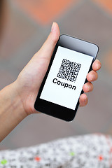 Image showing QR coupon on mobile display holding by woman hand