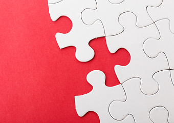 Image showing Incompleted white puzzle with red background