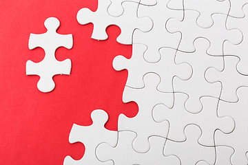 Image showing Incompleted white puzzle on red background