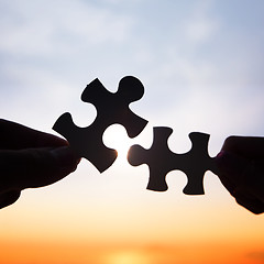 Image showing Two hands trying to connect puzzle pieces 