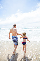 Image showing Father and young daughter walking into water at beach