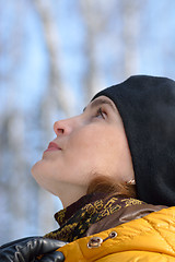 Image showing Woman in black beret and a yellow jacket with a hood. Looking up.