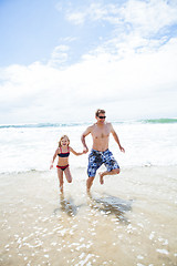 Image showing Happy father and daughter running from waves at beach