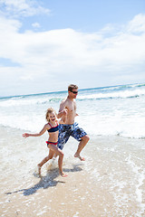 Image showing Happy father and daughter running along beach in shallow water
