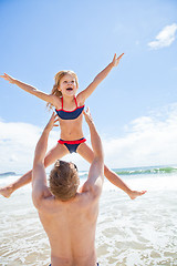 Image showing Father throwing young daughter in air at beach