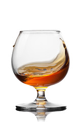 Image showing Splash of cognac in glass isolated on white background