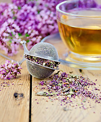 Image showing Herbal tea from oregano with strainer on board