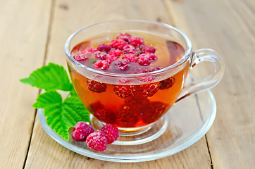 Image showing Tea with raspberry and leaf in a cup on board